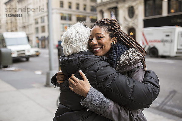 Frauen  die sich auf der Straße gegen Gebäude umarmen