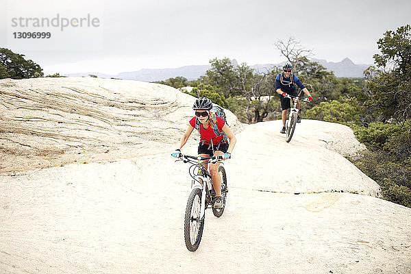 Fahrrad fahrende Paare auf Felsen vor klarem Himmel