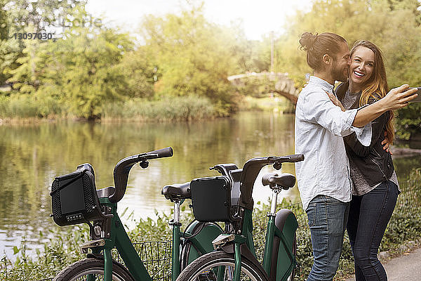 Mann nimmt Selbstliebe  während er seine Freundin am See küsst