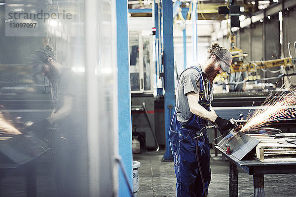 Arbeiter in Latzhose bei der Benutzung einer Schweißmaschine in einem Stahlwerk