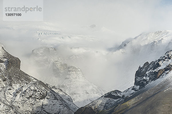 Panoramablick auf schneebedeckte Berge bei Nebel
