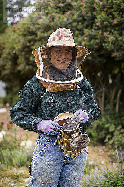 Porträt einer Bienenzüchterin in Arbeitsschutzkleidung  stehend im Betrieb