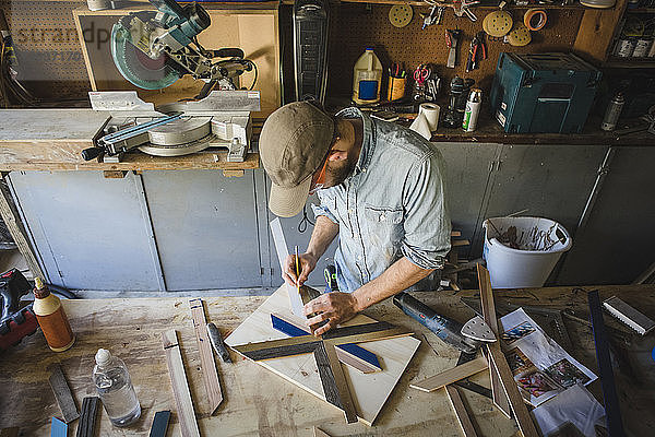 Hochwinkelansicht eines Künstlers  der Holzkunst an der Werkbank in der Werkstatt herstellt