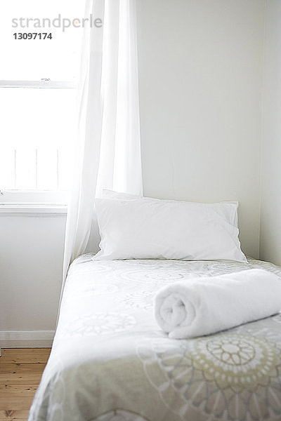 Kissen und zusammengerollte Decke im Bett am Fenster zu Hause