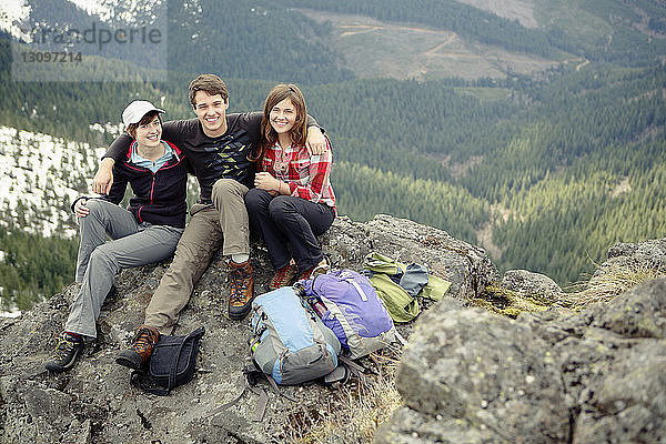 Porträt von glücklichen Freunden  die auf dem Berggipfel sitzen