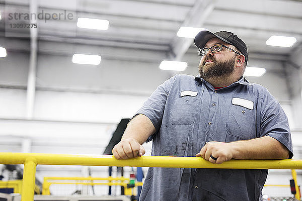 Arbeiter schaut weg  während er in einer Fabrik der Stahlindustrie steht