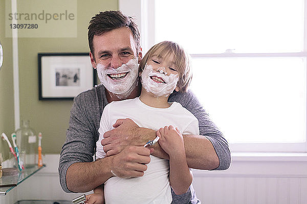 Porträt von glücklichen Vater und Sohn mit Rasierschaum im Gesicht im Badezimmer stehend