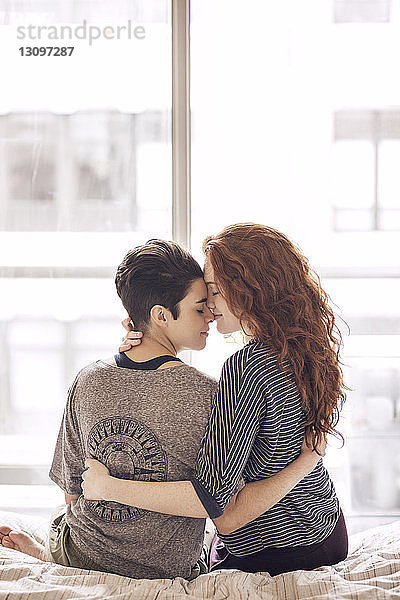 Lesbisches Paar  das zu Hause im Bett sitzt