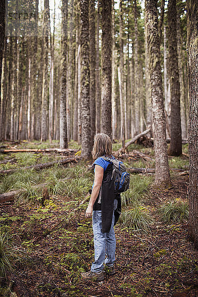 Frau trägt Rucksack  während sie im Wald steht