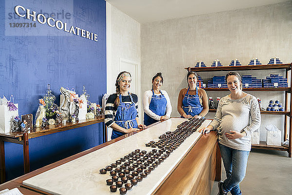 Porträt von lächelnden Mitarbeitern  die bei Tafelschokolade im Laden stehen
