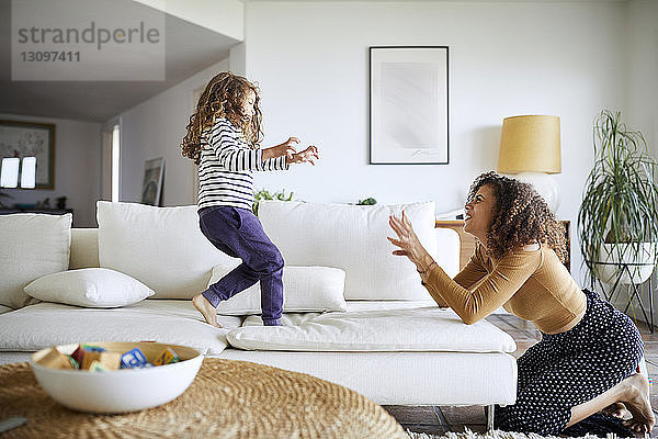 Seitenansicht einer glücklichen Mutter  die mit ihrer Tochter im Wohnzimmer spielt