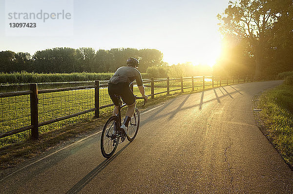 Männlicher Athlet fährt bei Sonnenschein auf Straße und Feld