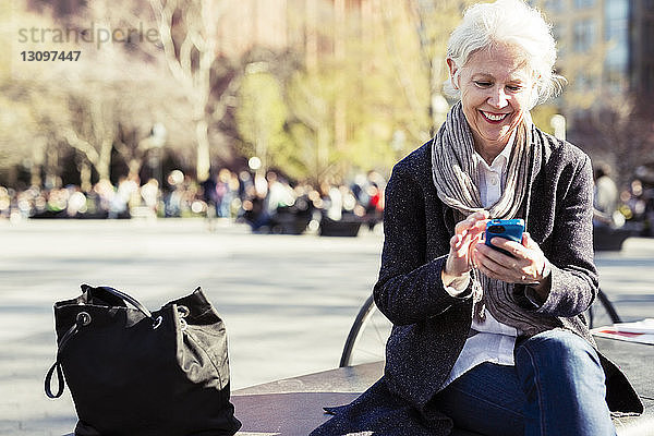 Glückliche ältere Frau mit Smartphone in der Stadt