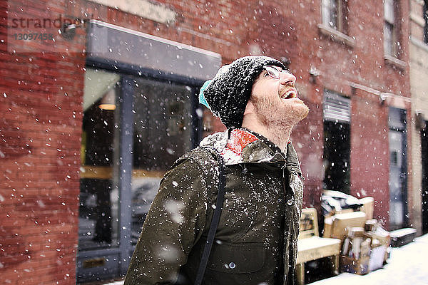 Glücklicher Mann genießt Schnee in der Stadt
