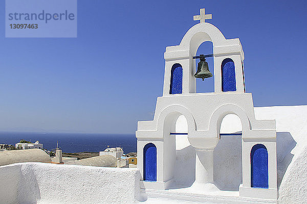 Blick auf den Glockenturm der Kirche Gegen Meer und blauen Himmel