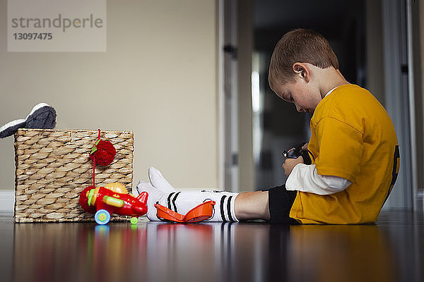 Seitenansicht eines Jungen  der mit Spielzeug spielt  während er zu Hause auf dem Boden sitzt