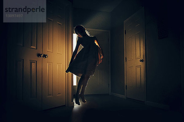 Glückliches Mädchen springt zu Hause in der Dunkelkammer