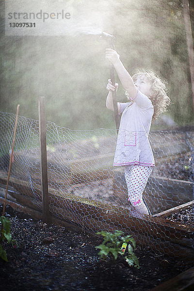 Seitenansicht eines Mädchens beim Spielen mit dem Gartenschlauch im Hof