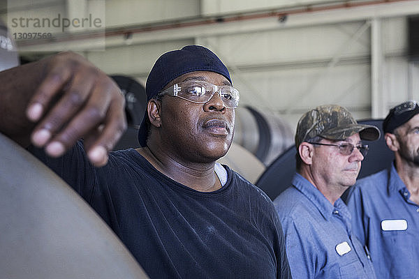 Ernste Arbeiter schauen weg  während sie in einer Fabrik der Metall-Stahlindustrie arbeiten