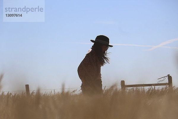 Seitenansicht einer Frau  die auf einem Grasfeld gegen den Himmel steht