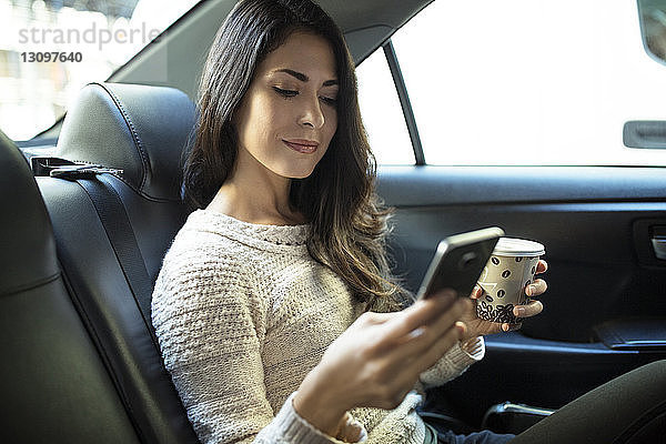 Junge Frau benutzt Smartphone im Taxi