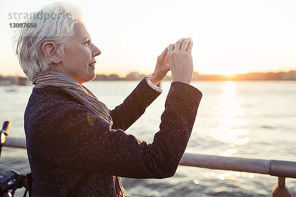 Ältere Frau fotografiert bei Sonnenuntergang auf See