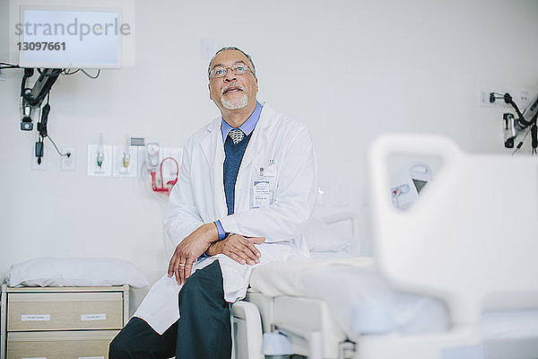 Männlicher Arzt sitzt im Bett auf der Krankenhausstation