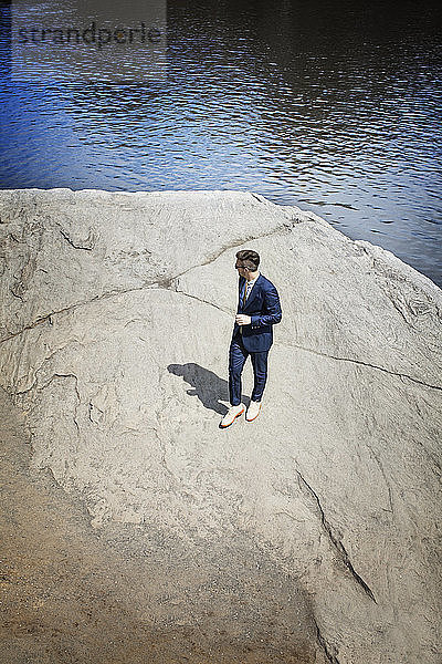 Hochwinkelaufnahme eines Mannes  der auf einem Felsen am See steht