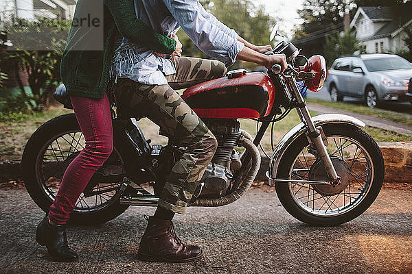 Niedriger Teil des auf dem Motorrad sitzenden Paares