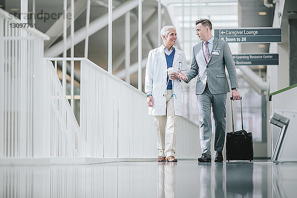 Männliche Ärzte sprechen beim Gehen im Krankenhauskorridor