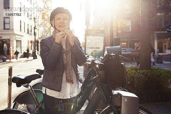 Nachdenkliche ältere Frau mit Helm  die an Fahrrädern steht