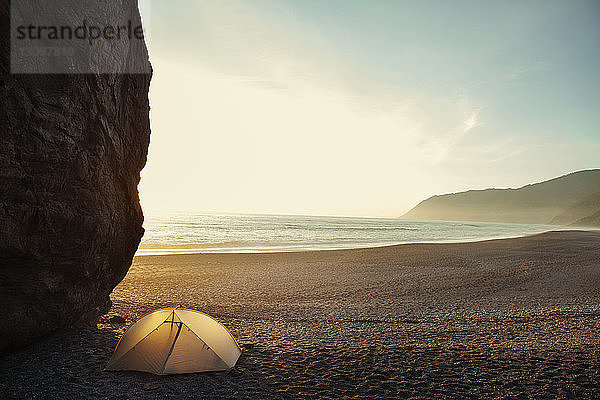 Zelt an einer Klippe am Strand gegen klaren Himmel bei Sonnenuntergang