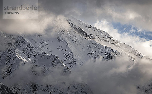 Landschaftliche Ansicht eines schneebedeckten Berges vor bewölktem Himmel