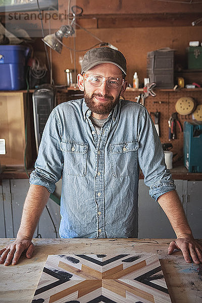 Porträt eines lächelnden Handwerkers mit Holzkunst an der Werkbank