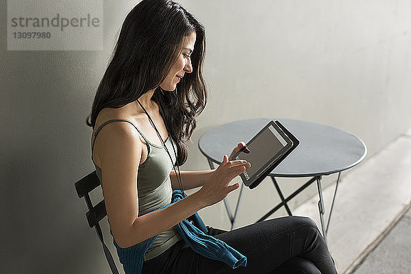 Junge Frau benutzt Tablet-Computer auf Stuhl im Freien
