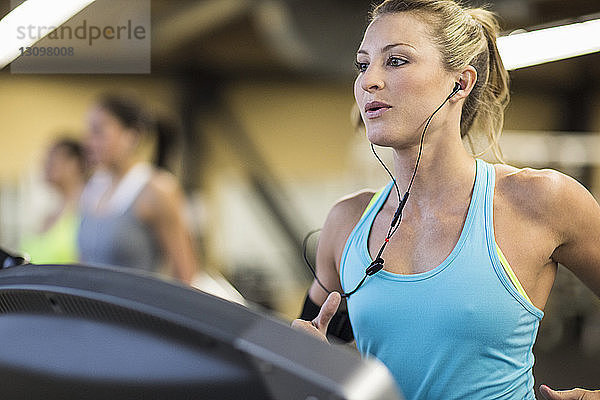 Frau schaut weg  während sie im Fitnessstudio auf dem Laufband trainiert