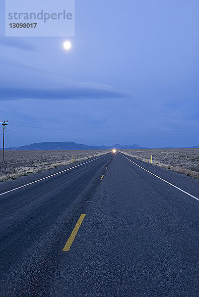 Straße inmitten der Wüste gegen den Himmel in der Abenddämmerung