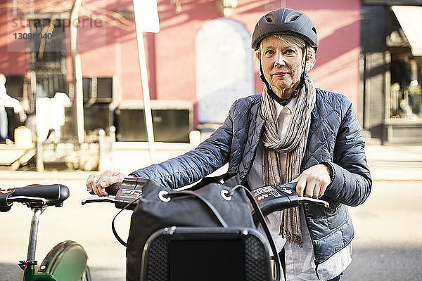 Porträt einer selbstbewussten älteren Frau  die mit dem Fahrrad auf der Straße steht