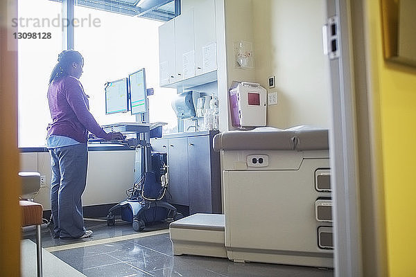 Ärztin benutzt Desktop-Computer im Behandlungszimmer