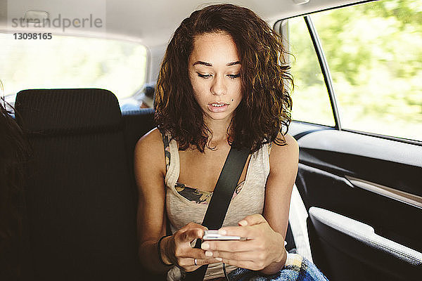 Frau benutzt Mobiltelefon auf Reisen im Auto