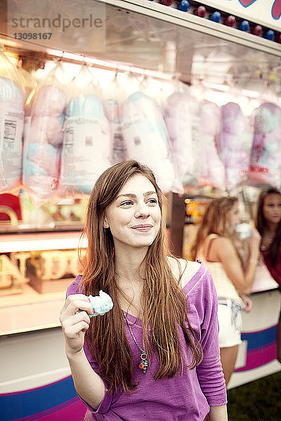 Teenager-Mädchen schaut weg  während sie Zuckerwatte am Verkaufsstand hält