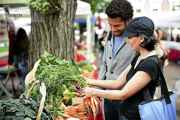 Multiethnisches Ehepaar kauft Gemüse am Marktstand