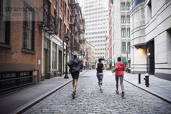 Rückansicht von multi-ethnischen Athleten  die auf der Straße in der Stadt laufen