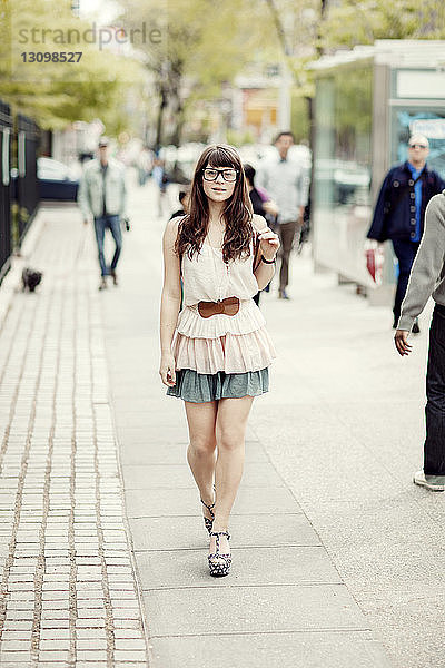 Porträt einer jungen Frau beim Gehen auf dem Bürgersteig