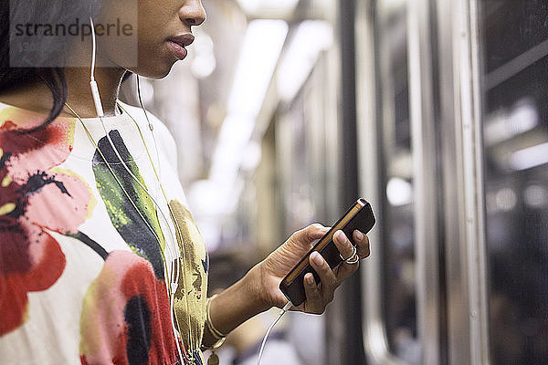 Frau  die während einer Zugfahrt Musik am Telefon hört