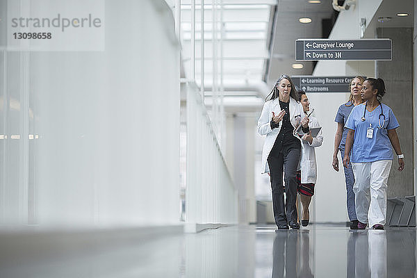 Ärztinnen diskutieren beim Gehen im Krankenhauskorridor