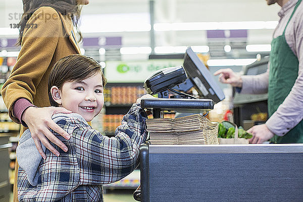 Porträt eines Jungen  der mit der Mutter im Supermarkt an der Theke steht