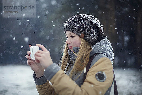 Frau fotografiert bei Schneefall per Handy