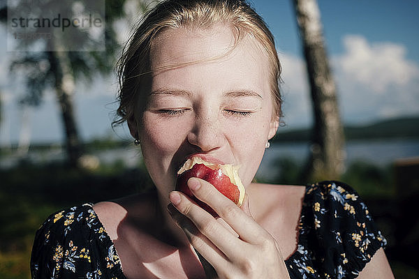 Frau isst Apfel an einem sonnigen Tag