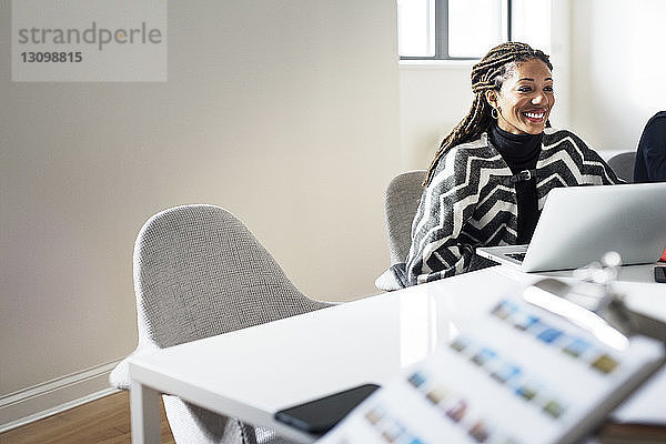 Lächelnde Frau  die während einer Besprechung im Büro am Tisch sitzt